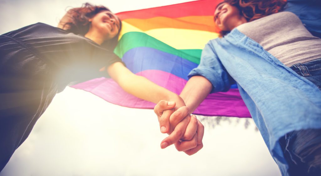 lgbtq couple holding hands under rainbow flag